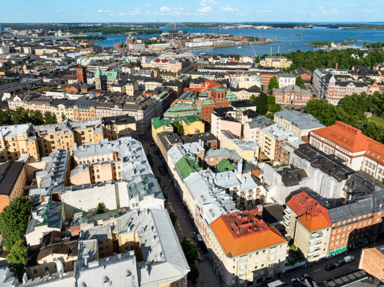 Ilmakuva Helsingin keskustasta, jossa näkyy värikkäitä rakennuksia ja taustalla satama.
